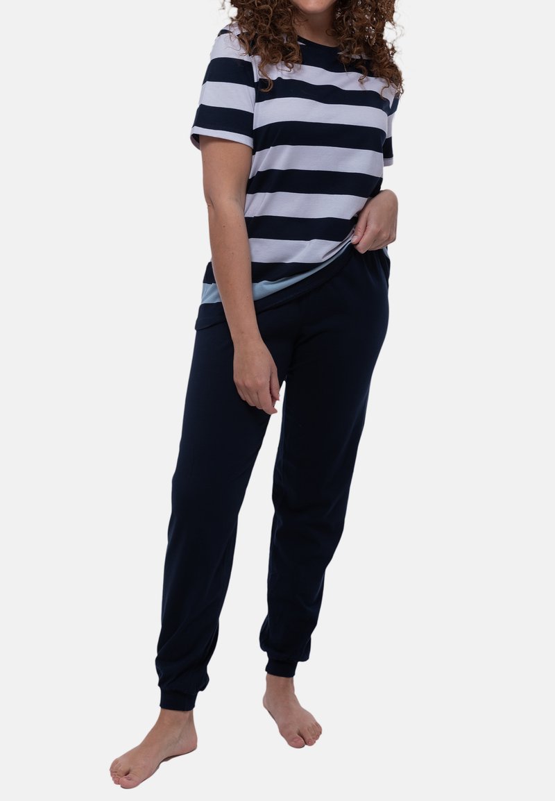 Raidallinen puuvillapaita tummansinisenä ja valkoisena, yhdistettynä tummansinisiin collegehousuihin. Housuissa on elastiset hihnat ja kiristettävä vyötärö mukavuutta varten.