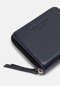 Portefeuille en cuir bleu marine avec une surface texturée, fermeture éclair dotée de quincaillerie en argent et une sangle latérale pour un transport facile.