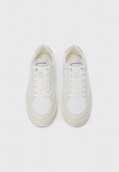 Beli supergi z opletenim tekstilnim zgornjim delom, gladkim gumijastim podplatom in toniranim poudarkom na peti. Ima ravne vezalke in jezik z blagovno znamko.