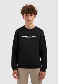 Zwarte sweatshirt met geribbelde manchetten en zoom, met de witte grafische tekst "BALLIN'" op de borst. Zacht materiaal, ronde hals ontwerp.