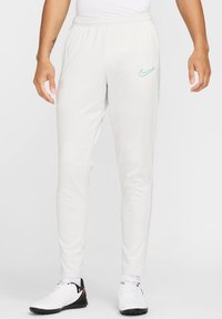 Slim-fit, hvide atletiske bukser med elastisk talje og lys blå Nike-logo accent. Har en glat tekstur og tapered ben.
