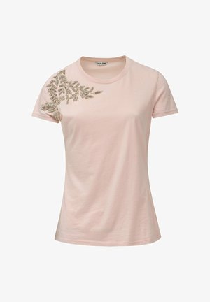 T-shirt rose clair à manches courtes avec un design de feuille perlée sur l'épaule gauche. Fabriqué en coton doux avec un col rond.
