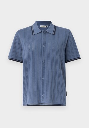 Kratka modra pletena srajca s kratkimi rokavi, gumbi in navpičnim progastim vzorcem ter temnim robom na ovratniku, rokavih in spodnjem robu.