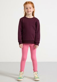 Mørkerød sweatshirt, lyserøde leggings og multicolor sneakers. Sweatshirten har rund hals og ribbede manchetter, mens leggingsene er tætsiddende.
