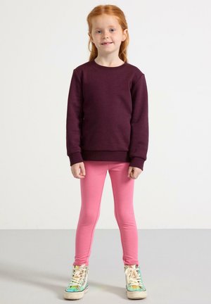 Mørkerød sweatshirt, lyserøde leggings og multicolor sneakers. Sweatshirten har rund hals og ribbede manchetter, mens leggingsene er tætsiddende.