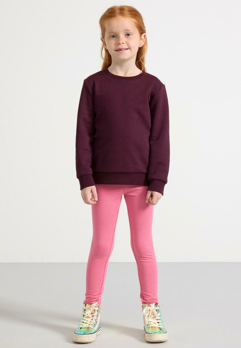 Mørkerød sweatshirt, lyserøde leggings og multicolor sneakers. Sweatshirten har rund hals og ribbede manchetter, mens leggingsene er tætsiddende.