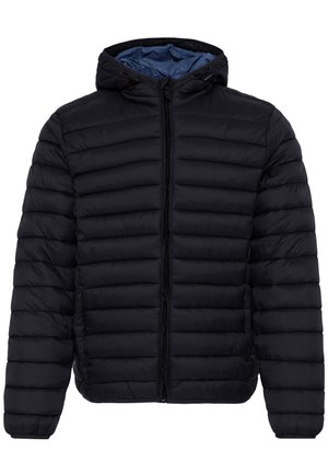 Mladý muž s krátkymi hnedými vlasmi, oblečený v čiernej prešívanej bunde so zipsom a kapucňou, pozerá sa vpravo na jednofarebnom pozadí.