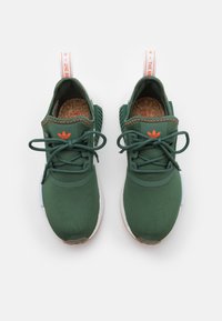 Pair of green lace-up athletic shoes with white soles and orange logo and stitching, viewed from above on a white background.