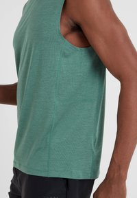 Green sleeveless athletic tank top made of textured fabric, featuring a crew neckline and side seams for a fitted look.