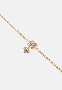 Pulseira com corrente torcida em tom de ouro, apresentando um pendente quadrado com gemas transparentes e um pequeno charm em forma de coração, também adornado com uma pedra.