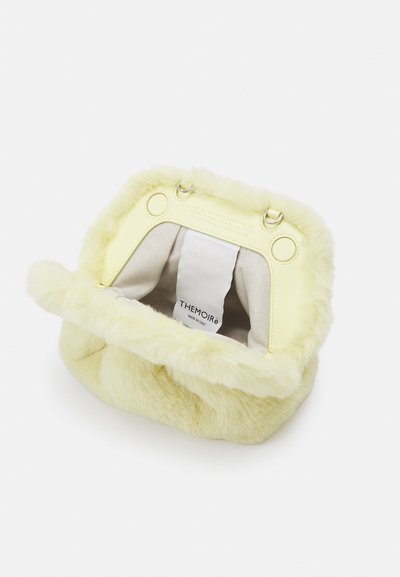 Bolsa de mão em pele sintética amarela suave, com interior creme, ferragens em metal e etiqueta de logo no interior; apresenta um formato arredondado e tampa dobrável.