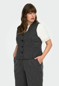 Grå randig väst med en figurnära design, fem knappar och en sidoficka. Bärs över en vit blus med spetskant.