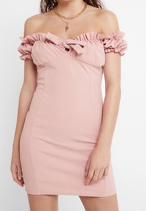 Vestido rosa ajustado con los hombros descubiertos, mangas con volantes y un detalle de nudo en el pecho, combinado con collares dorados en capas.