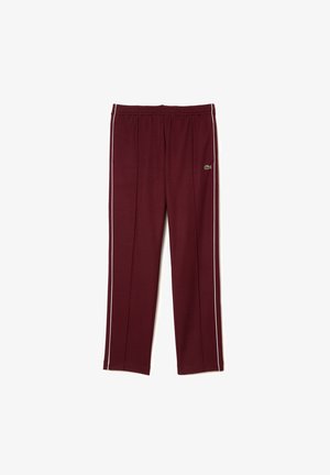 Pantalon de sport bordeaux avec liseré blanc sur les côtés, taille élastique et petit logo vert sur la cuisse supérieure.