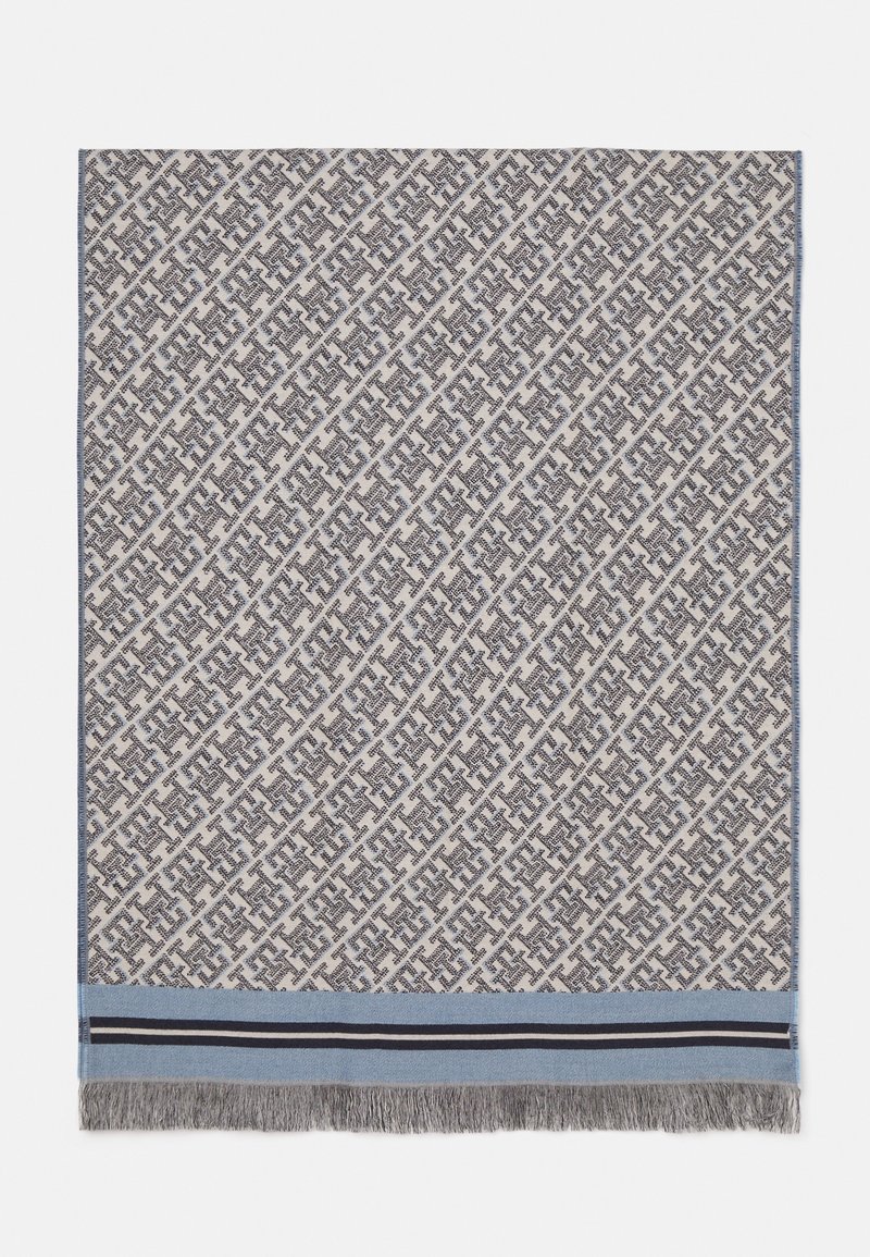 Tissu carré tissé avec des motifs géométriques diagonaux noirs et blancs répétés, bord bleu, rayures noires et blanches, et franges grises en bas.
