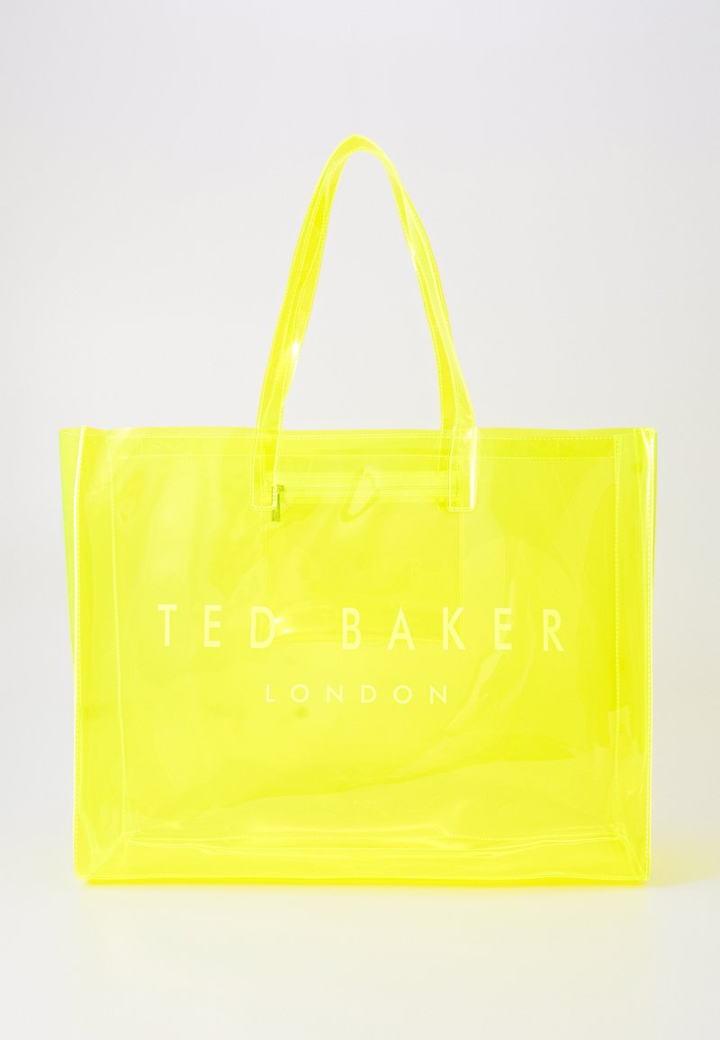 Gjennomsiktig gul tote-veske med to hender, med hvit "TED BAKER LONDON" tekst trykt på forsiden, glatt tekstur, rektangulær form.