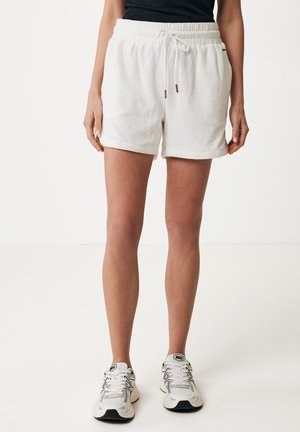 Shorts bianchi in cotone con finitura testurizzata, vita elastica e cordino. Presentano orlo ripiegato e tasche laterali. Indossati con sneakers chiare.