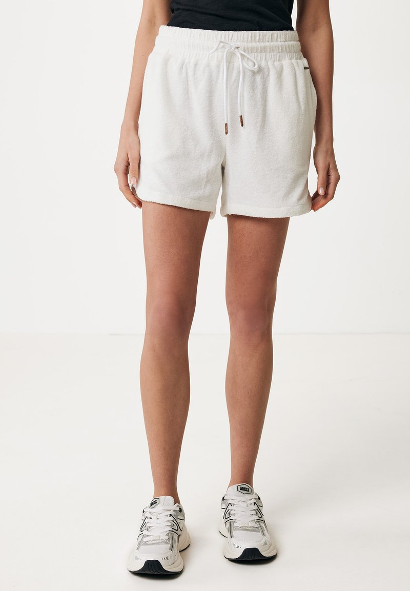 Shorts bianchi in cotone con finitura testurizzata, vita elastica e cordino. Presentano orlo ripiegato e tasche laterali. Indossati con sneakers chiare.