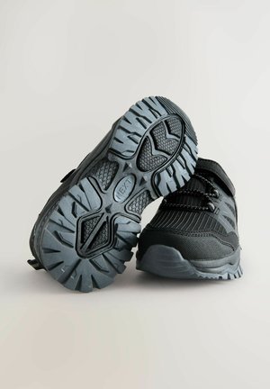 Scarpe da ginnastica nere con una superficie texturizzata, suole in gomma e lacci elastici. Caratterizzate da un design resistente e da un tallone imbottito per il supporto.