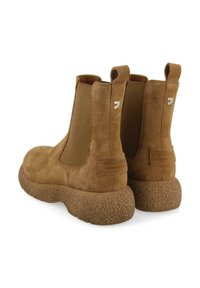 Bottines en suède marron avec des panneaux latéraux élastiques, semelles en caoutchouc texturé et un détail logo discret sur le talon, présentant une forme arrondie.
