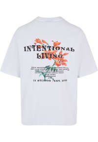 Tricou din bumbac alb cu un design floral, având flori portocalii și text negru pe spate. Croială lejeră cu mâneci scurte.