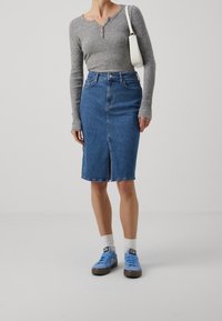 Harmaa pitkähihainen ribbineulepaita, vaaleansininen denimpencilhame, jossa etuhalkio, valkoinen käsilaukku ja siniset tennarit harmailla pohjilla sekä valkoiset sukat.