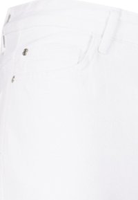 Jeans de mezclilla blanca con una textura suave, que presentan bolsillos estándar, acentos de metal y un diseño ajustado.