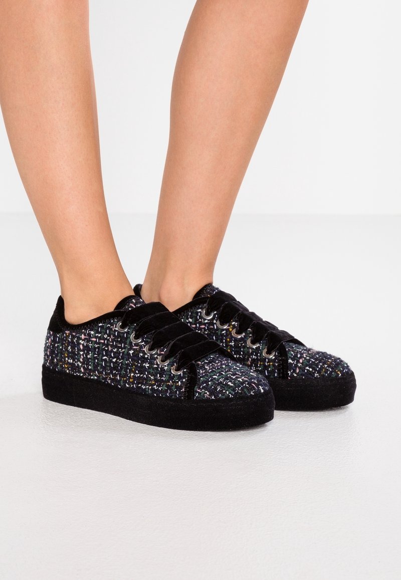 Svarta textilsneakers med ett flerfärgat vävt mönster, med en mjuk tygöverdela, snörning och en strukturerad svart sula.