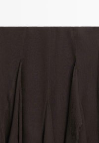 Jupe en tissu marron foncé avec des plis cousus verticalement créant un design texturé et structuré.