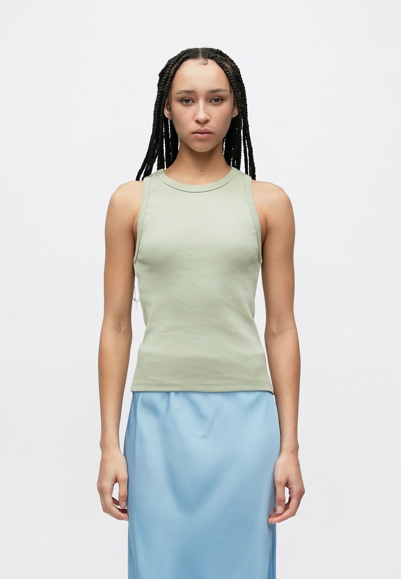 Haut débardeur côtelé vert clair avec un col rond, associé à une jupe en satin bleue. Le tissu est lisse avec une silhouette ajustée.