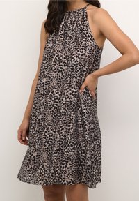 Robe sans manches à imprimé léopard en marron clair et noir, avec un encolure froncée et des poches latérales, fabriquée en tissu léger.