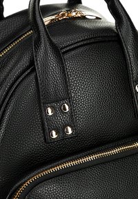 Zaino in pelle nera dalla texture morbida, con una forma arrotondata, dettagli in hardware dorato e cerniere visibili. Include due manici robusti.