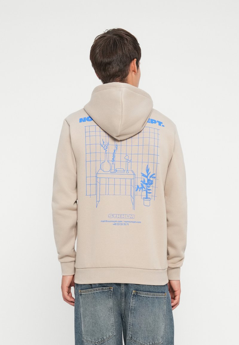 Beige hoodie with a blue graphic design featuring a table and plants. It has a drawstring hood and ribbed cuffs with a relaxed fit.