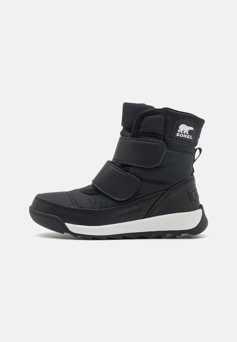 Botte d'hiver noire montant jusqu'au milieu du mollet avec deux sangles velcro, semelle blanche et logo ours polaire Sorel sur le revers.