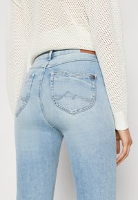 Ljusblå, högmidjade jeans med figurnära design. Har två hjärtformade bakfickor och subtila sömdetaljer. Mjuk denimtextur.