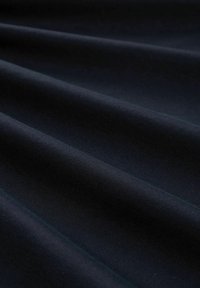 Tmavomodrý textil s hladkým povrchom, na ktorom sú viditeľné jemné, vlnité záhyby a jednotná matná povrchová úprava.