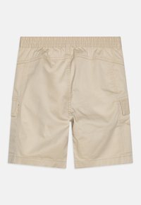 Beżowe szorty typu cargo wykonane z lekkiego materiału, wyposażone w elastyczny pas i boczne kieszenie. Gładka faktura z wzmocnionymi szwami.