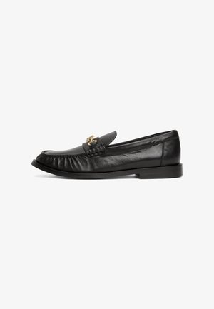 Black leather loafer shoe with a rounded toe, pleated design, and gold-tone hardware accents on the upper. Flat black sole.