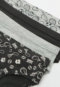 Tres pares de calzoncillos de hombre: uno gris con íconos deportivos, uno negro liso, uno negro con un patrón de equipamiento deportivo y el texto "NYC".