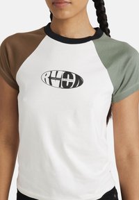 White T-shirt with raglan sleeves in brown and green. Features a black oval logo with text, ribbed black neckline, and short sleeves.
