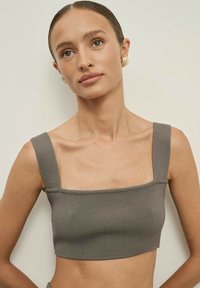 Szürke bordázott crop top széles négyzet alakú p�ántokkal, testre simuló fazon, textúrált anyag és letisztult alsó szegély, amely a minimalista esztétikát tükrözi.