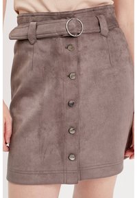 Mini-jupe en daim taupe avec une taille haute, dotée d'une large ceinture en métal argenté et de six boutons en métal sur le devant.