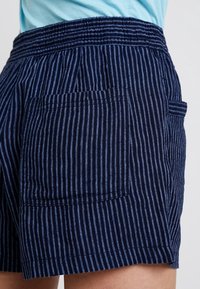 Marineblauwe gestreepte shorts met een elastische tailleband, voorzien van twee achterzakken en een zachte textuur, geschikt voor casual wear.