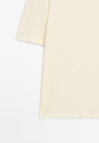 Krémové krátké tričko s rukávem vyrobené z měkké bavlny, s volným střihem a hladkou texturou. Jednoduchý a klasický design.
