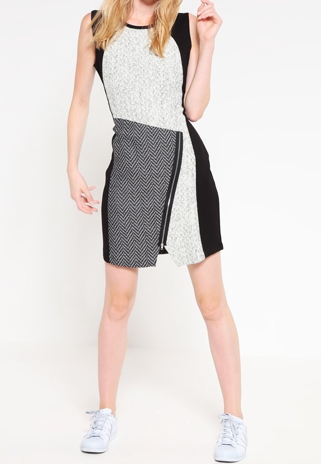 Robe sans manches en noir et blanc avec motif texturé, panneaux contrastants et fermeture éclair à l'avant. Associée à des baskets blanches.