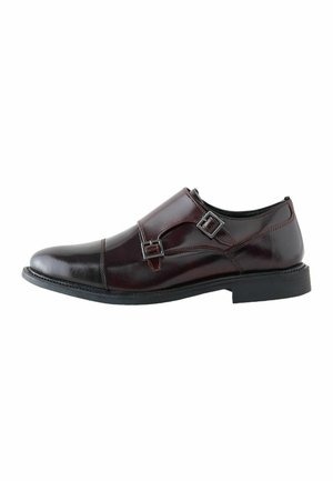 Dunkelbrauner Herrenschuh aus Leder mit doppelten Monk-Riemen und schwarzer Sohle, seitlich auf weißem Hintergrund gezeigt.