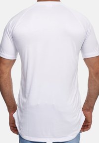 Camiseta blanca de manga corta con cuello redondo, textura suave y un dobladillo trasero ligeramente más largo. Diseño de un solo color sin patrones.