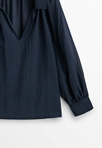 Granatowa, długorękawowa bluzka, wykonana z lekkiego, teksturowanego materiału, z głębokim dekoltem w serek i marszczonymi mankietami dla dodatkowej objętości.