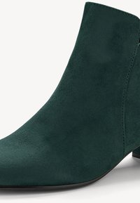 Zelené semišové kotníkové boty s špičatou špičkou, hladkým povrchem a nízkým blokovým podpatkem. Minimální prošívání zdůrazňuje elegantní design.