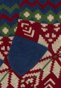 Calze lavorate a maglia con un motivo geometrico rosso, blu e verde con dettagli bianchi e un tallone blu solido. Materiale dalla texture morbida.